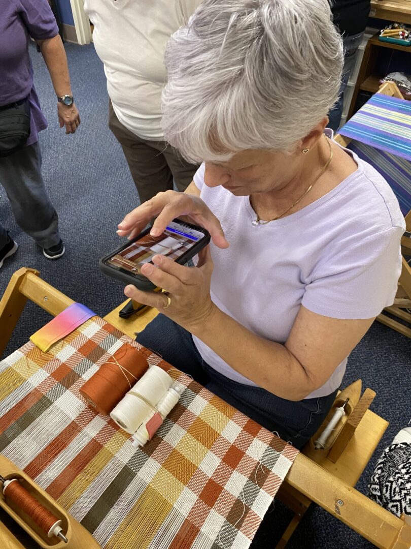 A weaver snaps a photo of her beautiful work and thread colors.