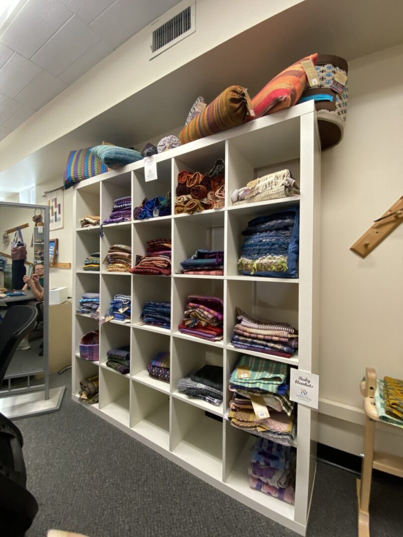 A colorful shelf of finished weavings