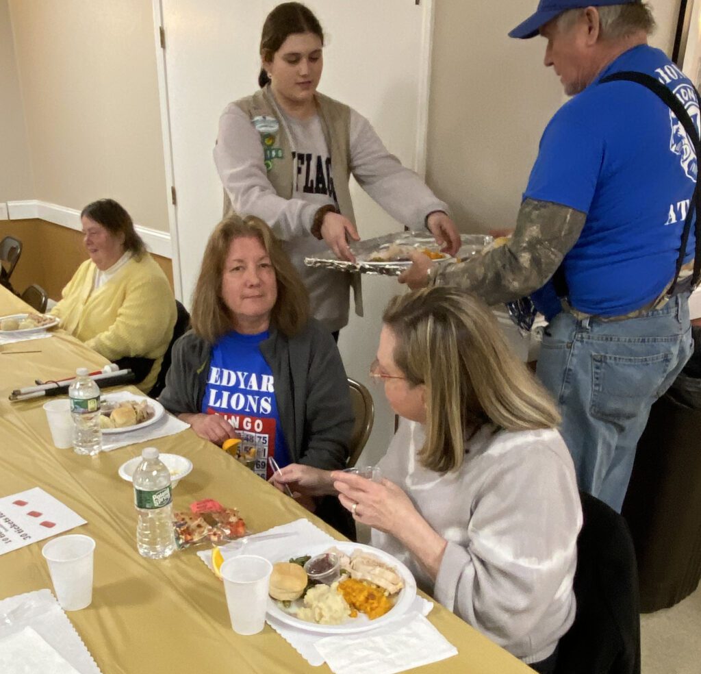 Girl Scout and Lion serve turkey dinner.